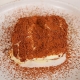 Et stykke tiramisu serveret med drysset kakaopulver